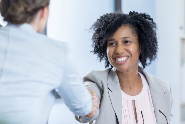 Confident CEO greets potential employee before job interview. The interviewee's back is to the camera.